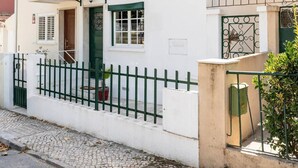 A white building with a green door, a balcony, and a metal fence. - BBQ, Easy Parking & near Tejo, Lisbon Garden Stays (Lisboa)