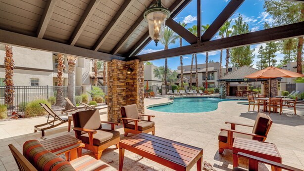 An outdoor pool area with lounge chairs and a stone pillar. - Scottsdale Extended-Stay Condo w/ Pool Access (Scottsdale)