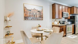 A dining area with a round table, chairs, and a painting of a building on the wall. - Scottsdale Extended-Stay Condo w/ Pool Access (Scottsdale)