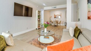 A modern living room with a flat-screen TV, a glass coffee table, and a sofa with decorative pillows. - Scottsdale Extended-Stay Condo w/ Pool Access (Scottsdale)
