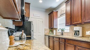 A kitchen with granite countertops, wooden cabinets, a coffee maker, and a kettle. - Scottsdale Extended-Stay Condo w/ Pool Access (Scottsdale)