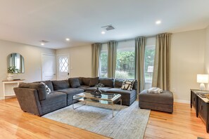 A modern living room with a sectional sofa, a glass coffee table, and a matching ottoman.