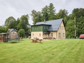 A two-story house with a green roof, a wooden deck, and picnic tables in a grassy yard. - Apartment Meda by Interhome (Rudnik)