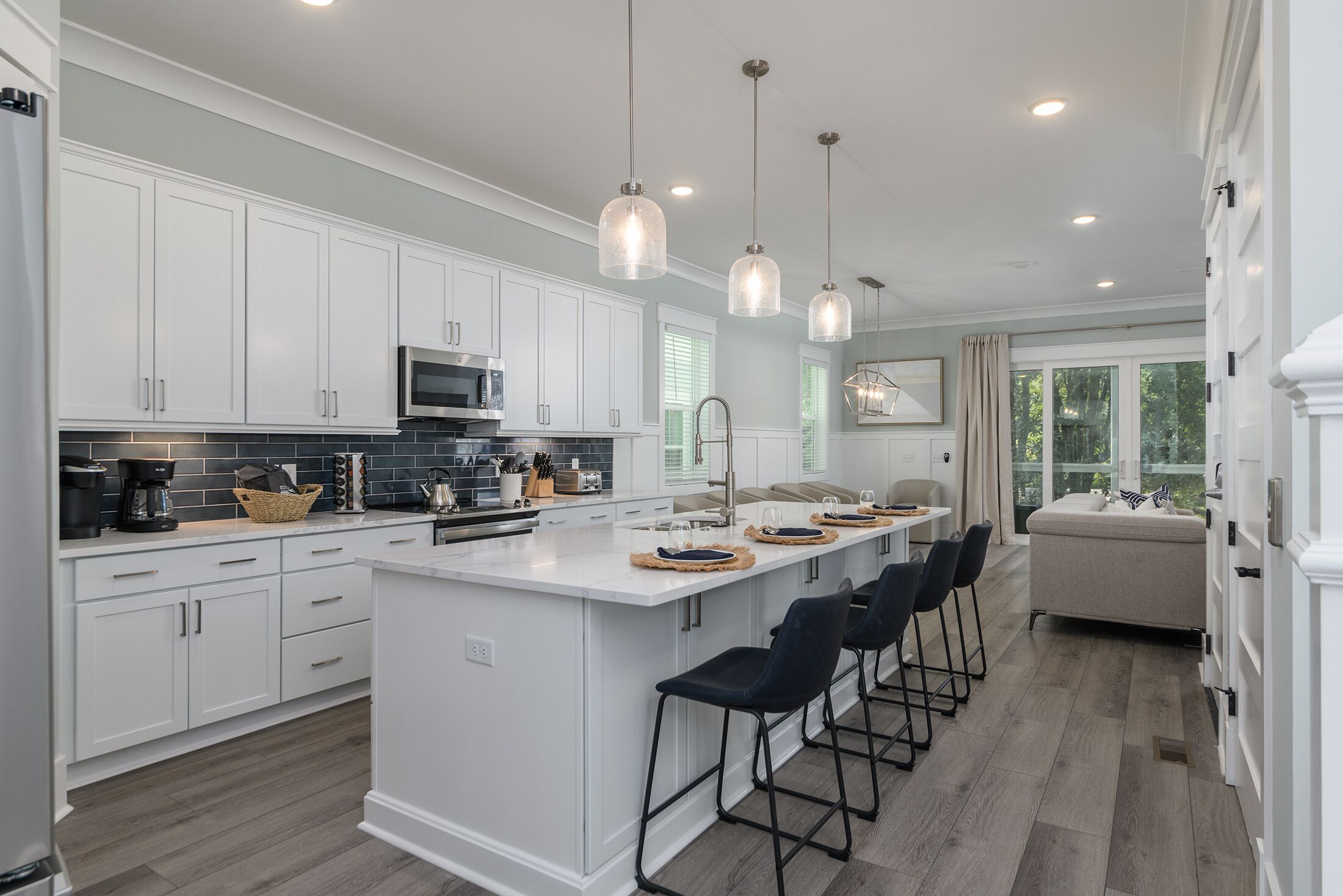 A modern kitchen with white cabinetry, a central island with bar stools, and pendant lighting.