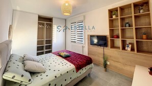 Une chambre à coucher comprenant un lit, une télévision, une armoire et une étagère.