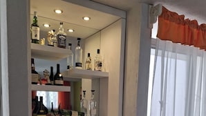 Eine Bar mit Regalen voller Spirituosenflaschen und einem Spiegel, der den Raum wiedergibt.
