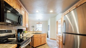 A modern kitchen with wooden cabinets, stainless steel appliances, and a tiled floor. - 2BR Cozy Getaway Awaits with High-Speed Wi-Fi! (Park City)