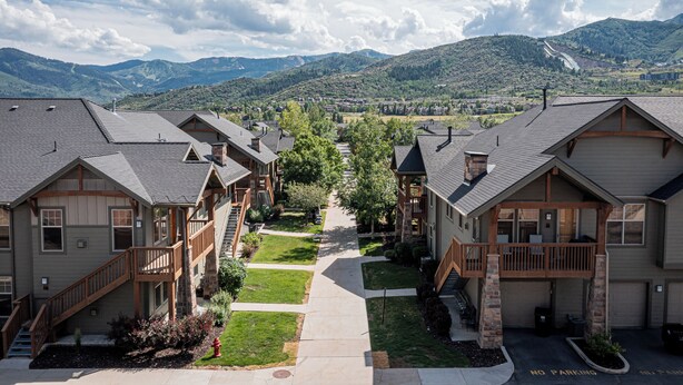 A residential area with multiple two-story houses featuring balconies, a central walkway, and a mountainous backdrop. - 2BR Cozy Getaway Awaits with High-Speed Wi-Fi! (Park City)