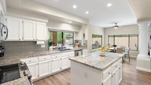A spacious kitchen with white cabinets, granite countertops, and a large island. - Sunset Paradise l Waterslide l Heated Pool l Hot Tub l Putting Green (Scottsdale)