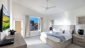 A modern bedroom with a large bed, a desk, a television, and a balcony with curtains. - Cactus Grove l Heated Pool l Putting Green l BBQ (Scottsdale)