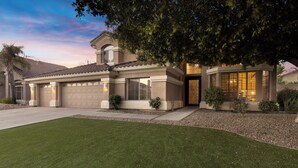 A residential house with a garage, a well-maintained lawn, and a large tree providing shade. - Cactus Grove l Heated Pool l Putting Green l BBQ (Scottsdale)