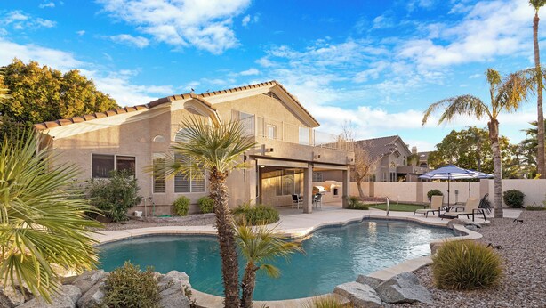 A two-story house with a swimming pool, surrounded by rocks and palm trees. - Cactus Grove l Heated Pool l Putting Green l BBQ (Scottsdale)