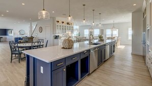 A spacious kitchen with a central island, pendant lighting, and a view to the dining area. - Royal Shell North | Oceanfront | Private Pool and Hot Tub (Virginia Beach)