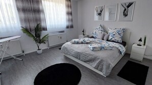 A modern bedroom with a bed, bedside tables, a radiator, a potted plant, and artwork on the wall. - Vacation apartment 90 m2, 2 minutes walk to the hospital in the center of Sulzbach  (Sulzbach/Saar)