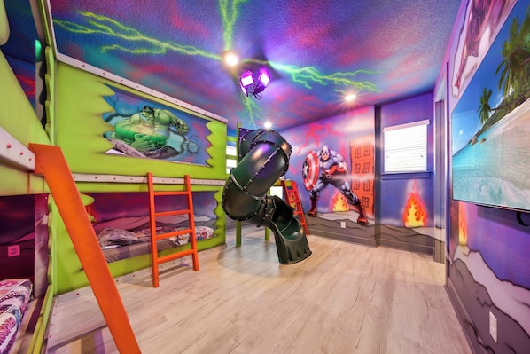 Une pièce avec des lits superposés, une échelle et un plafond muni d’un luminaire.
