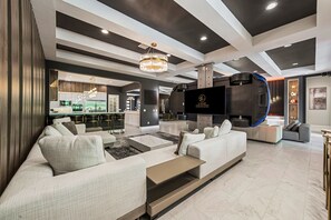 A modern living room with a sofa, coffee table, and a TV. There is a kitchen area in the background.