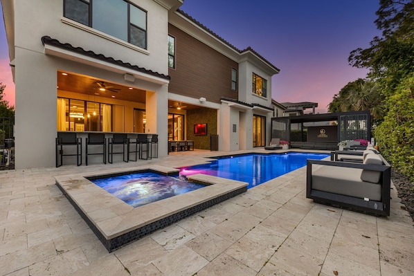 A modern house with a swimming pool, outdoor seating, and a bar area.