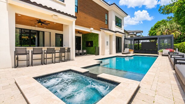 A modern outdoor pool area with a hot tub, bar seating, and a covered patio. - The Immersive Estate at Reunion - Theme Park Inside Your Vacation Home (Kissimmee)