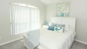 Una camera da letto con un letto, un comodino e un quadro appeso al muro.