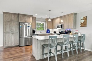 A modern kitchen with wooden cabinets, stainless steel appliances, and a central island with bar stools.