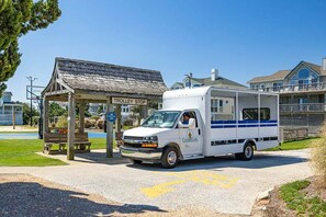 A white truck with a blue stripe parked at a trolley stop. - Sailors Rest | 844 ft to the beach (Corolla)