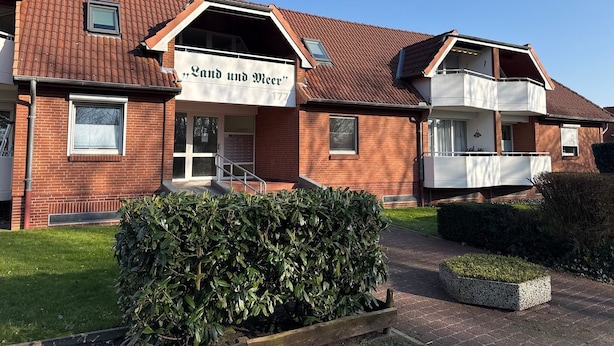 A two-story building with a sign reading 'Land und Meer' and a small balcony on the upper floor. - Fewo14 - Haus Land & Meer (Cuxhaven)