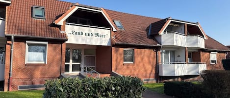 A two-story building with a sign reading 'Land und Meer' and a small balcony on the upper floor.
