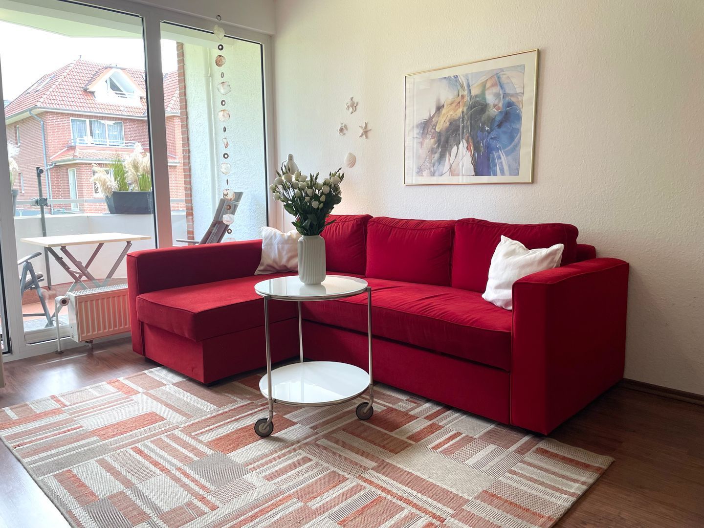 Ein rotes Sofa, ein weißer Tisch und ein Gemälde an der Wand.