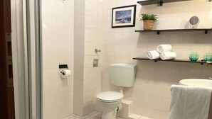 A bathroom with a toilet, a shower, a sink, and a towel rack.