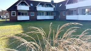 A two-story residential building with a sloped roof, multiple balconies, and a grassy yard. - Fewo14 - Haus Land & Meer (Cuxhaven)