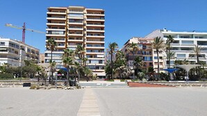 A multi-story hotel with balconies, palm trees, and a construction crane in the background. - Apartamento 3 Habitaciones Primera Linea de Playa (Estepona)