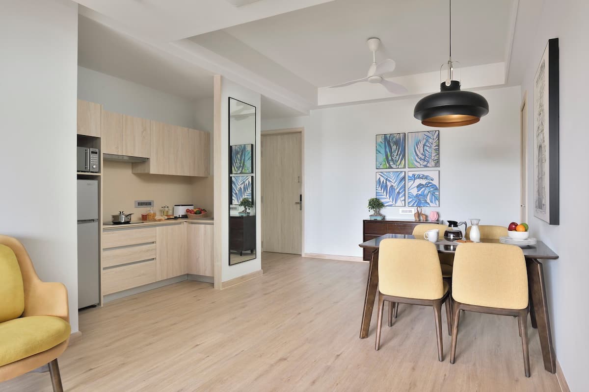Una cocina moderna con armarios de madera, un comedor con mesa y sillas, y un ventilador de techo.