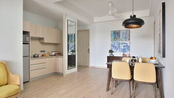 A modern kitchen with wooden cabinets, a dining area with a table and chairs, and a ceiling fan.