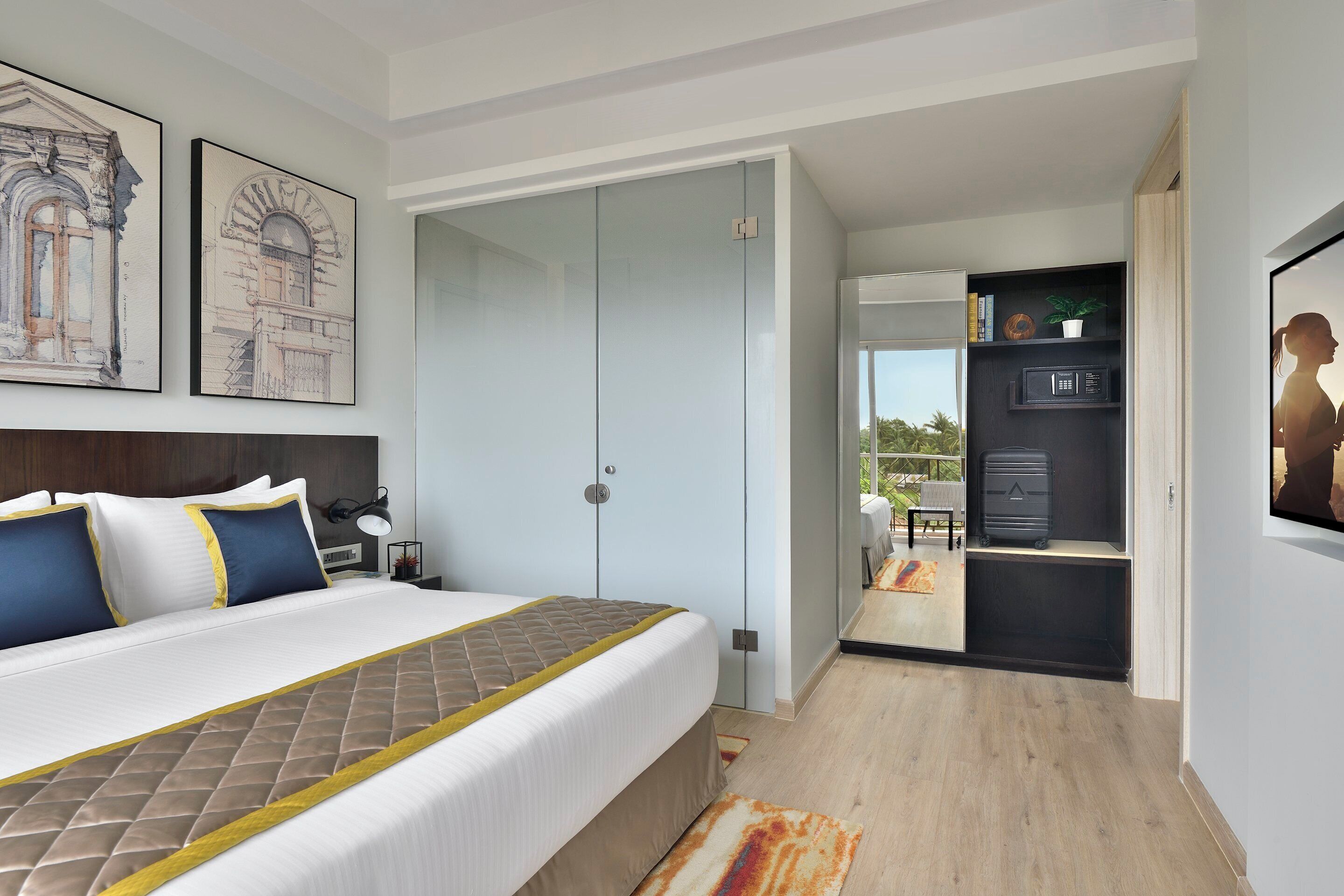A modern hotel room with a large bed, a walk-in closet, a kitchenette, and a balcony with a view.