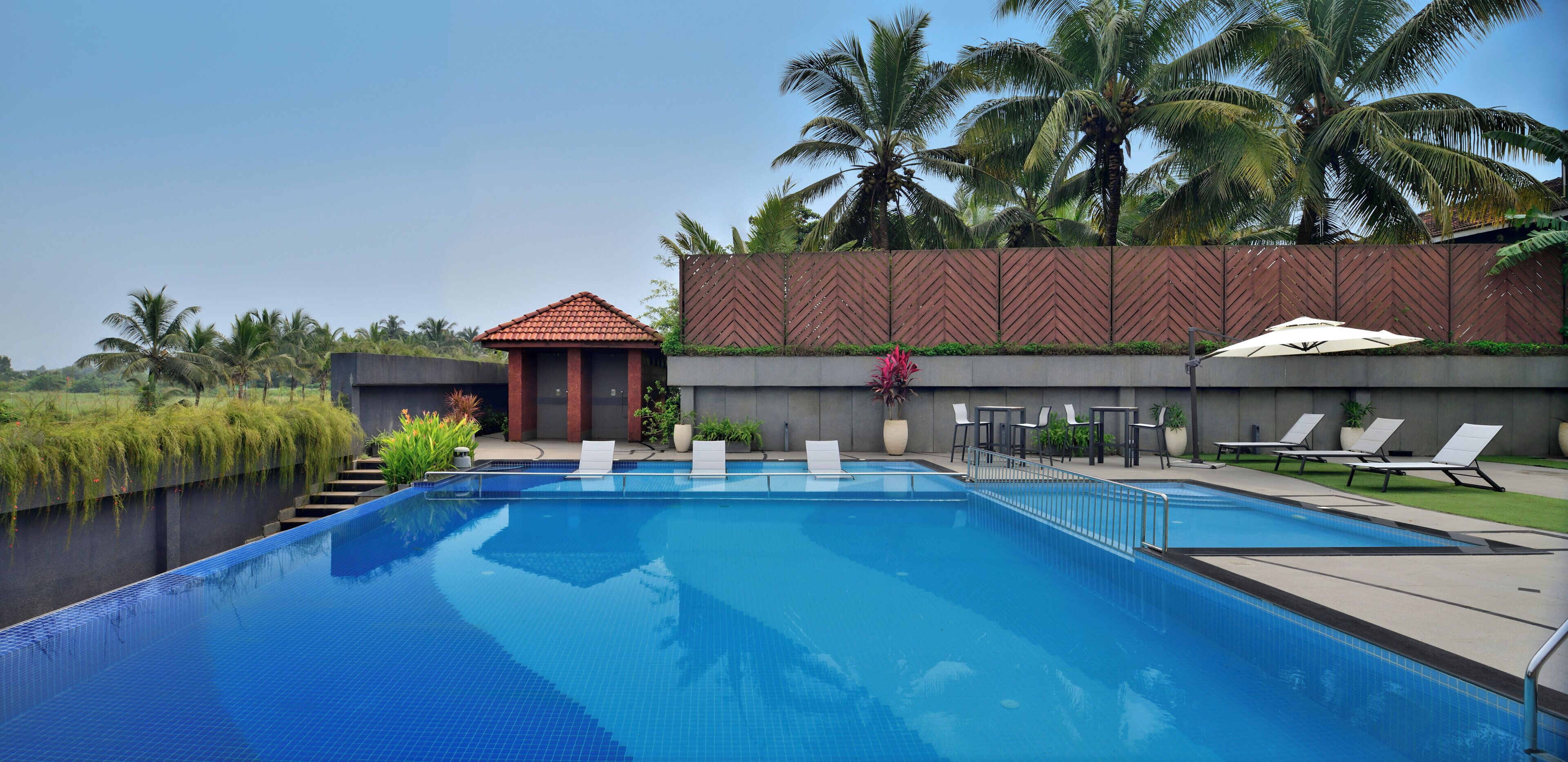 A swimming pool with lounge chairs and a small pavilion.