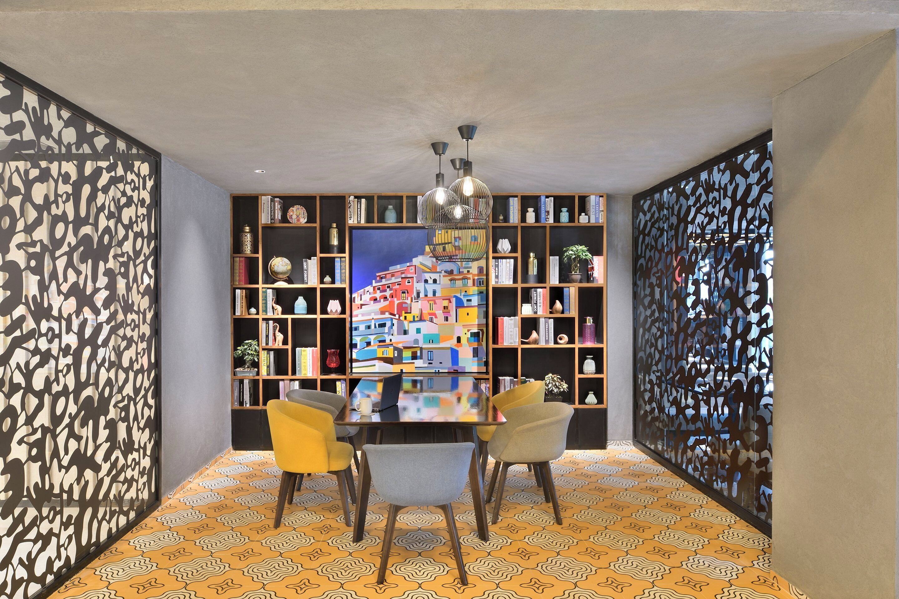 Un comedor con una mesa de vidrio, cuatro sillas y un cuadro colorido en la pared.