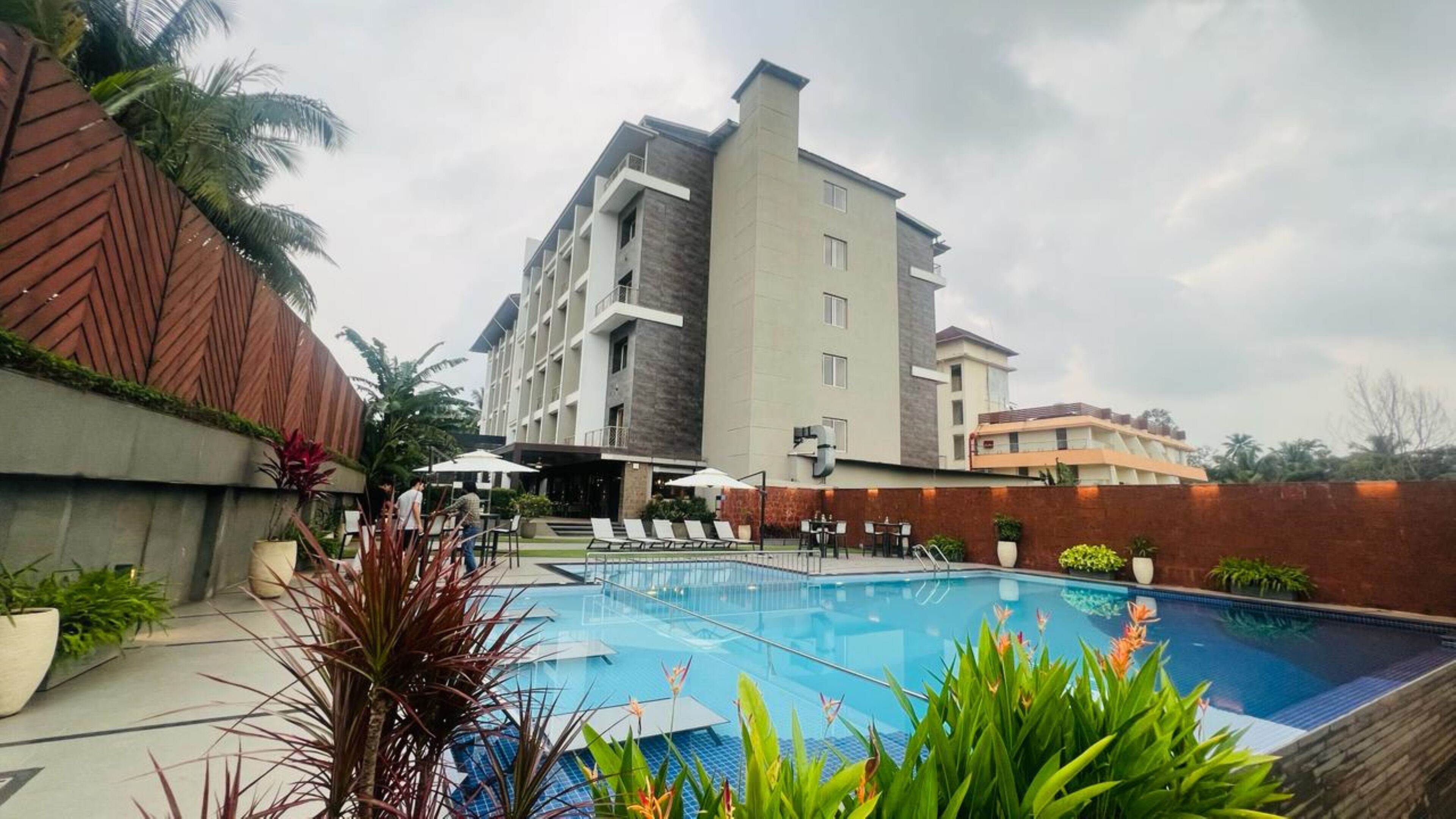 Un hotel con piscina, mobiliario exterior y un diseño de edificio moderno.
