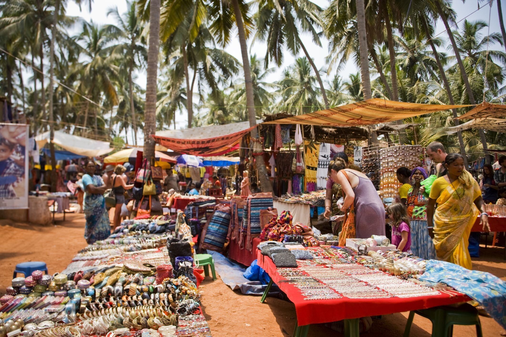A bustling outdoor market with various stalls selling textiles and jewelry.