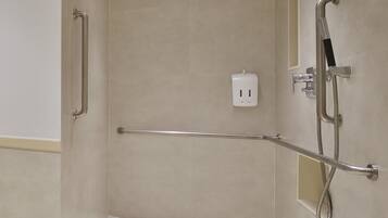 Un baño moderno con cabina de ducha, barras de apoyo y ducha de mano.