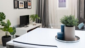 A modern living room with a white sofa, a flat-screen TV, and a coffee table with decorative items.
