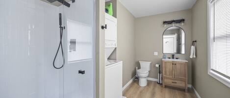Une salle de bain moderne dotée d’une douche à parois de verre, de toilettes et d’un meuble-lavabo avec un miroir.