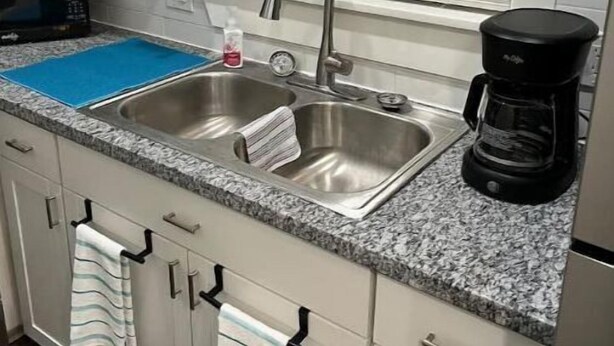 Una cocina con un lavamanos doble, una cafetera y un microondas.