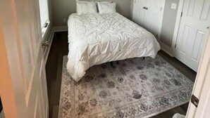 Un dormitorio con cama, ventilador de techo, aire acondicionado y una alfombra estampada.