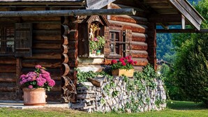 A rustic log cabin with a stone wall and a wooden porch. - Ferienwohnung Jennerblick, 85 qm, 1-4 Personen, 2 Separate Schlafzimmer, Wohn- Esszimmer, Bad, Balkon (Schönau am Königssee)
