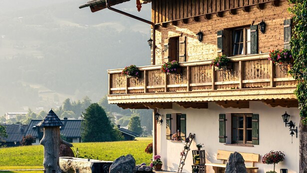 A traditional chalet with a balcony adorned with flower boxes, a stone pathway leading to the entrance, and a rustic wooden fence. - Ferienwohnung Jennerblick, 85 qm, 1-4 Personen, 2 Separate Schlafzimmer, Wohn- Esszimmer, Bad, Balkon (Schönau am Königssee)