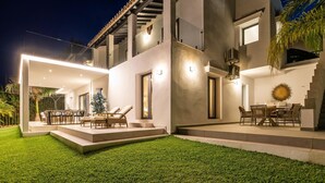 A modern two-story house with a patio area, outdoor seating, and a well-maintained lawn. - Top Renovated 4BDRM Luxury Villa - Frontline Golf (Benahavís)