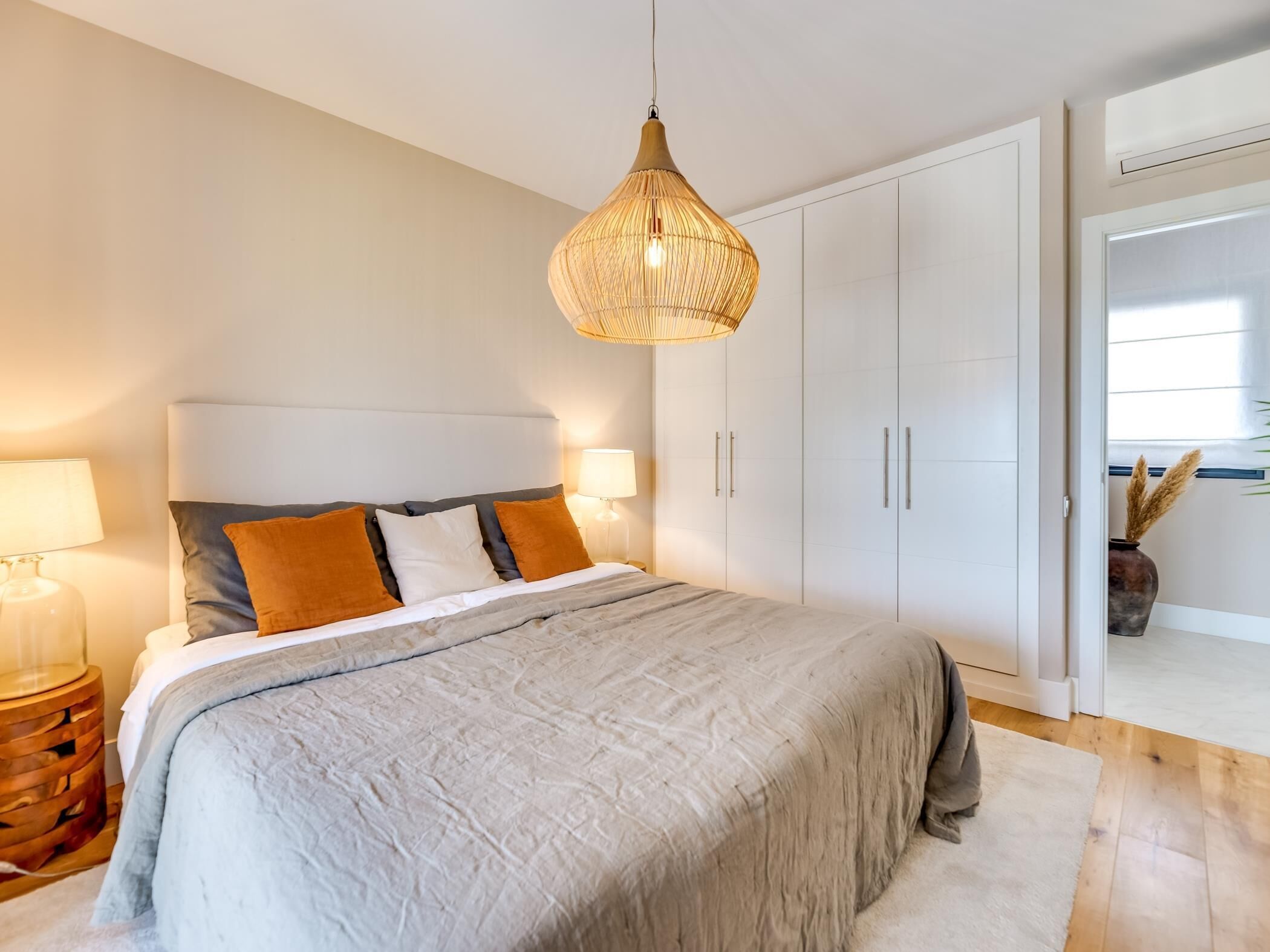 Een moderne slaapkamer met een groot bed, een witte garderobe en een hanglamp.