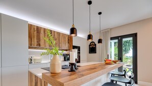 A modern kitchen with a wooden island, pendant lights, and a view to the outside. - Top Renovated 4BDRM Luxury Villa - Frontline Golf (Benahavís)