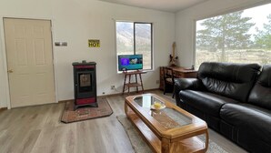 A living room with a fireplace, a television, a guitar, and a leather couch.