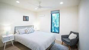 A bedroom with a bed, nightstand, chair, window, and ceiling fan. - Downtown Bend Vacation Cottage (Bend)